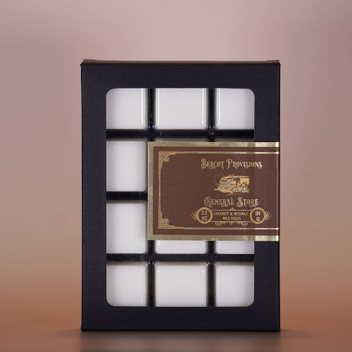 Pack of white wax melts in a black box with a gold label on a brown background