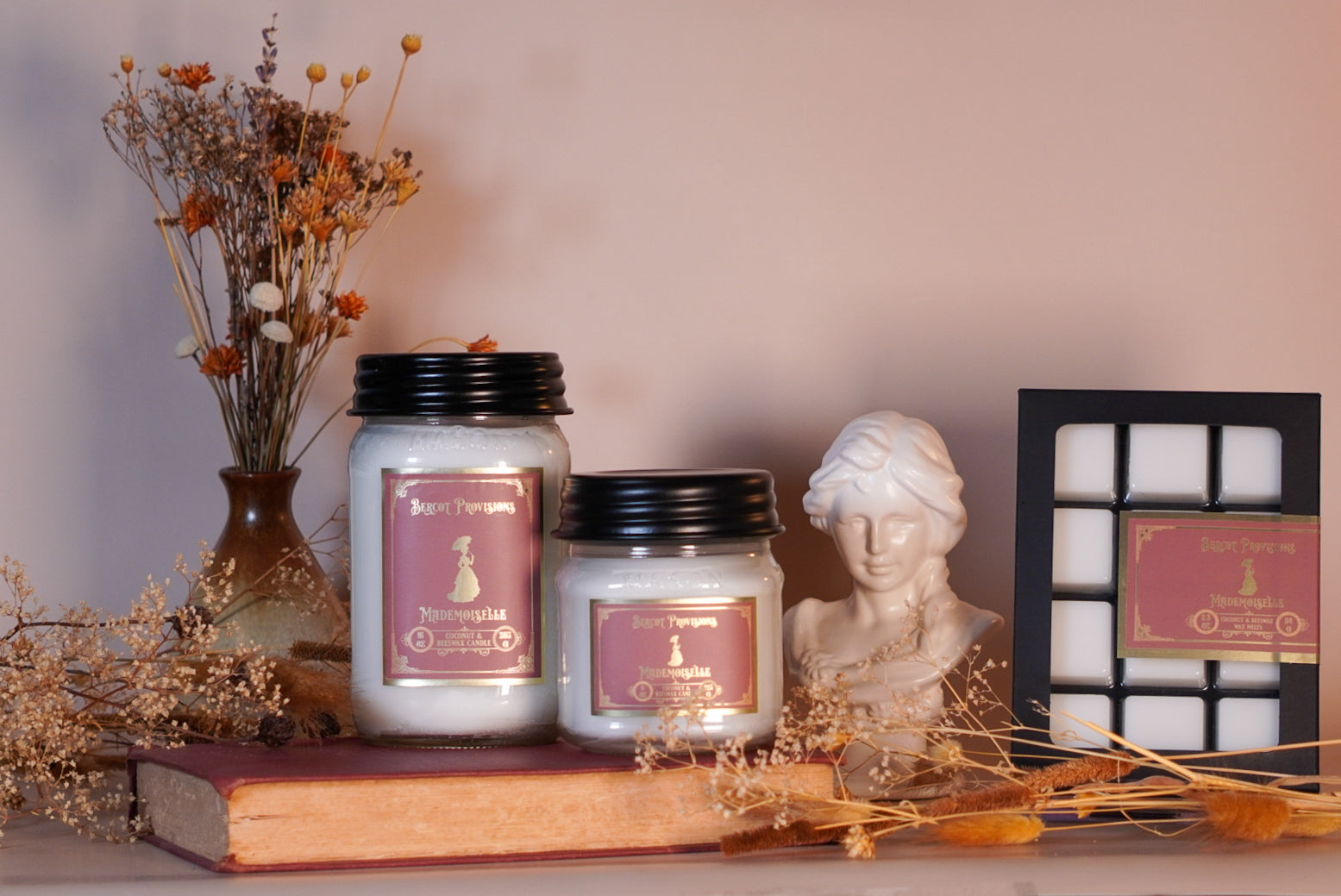 Candles and wax melts with decorative elements on a shelf against a neutral background