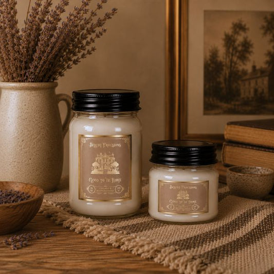 Two candles with labels on a rustic surface with decorative elements.