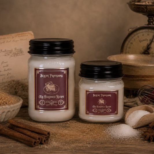 Two jars of 'Old Fashioned Recipe' candles on a rustic wooden surface with spices and a scale in the background.